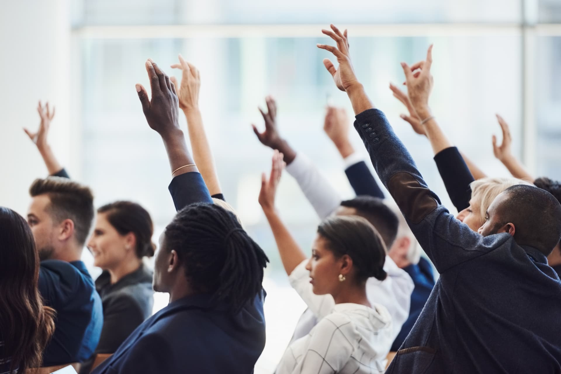 Supporters at a meeting raising their hands to volunteer